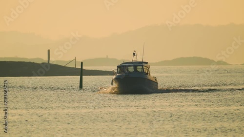Motorboat cruising through calm coastal waters during golden evening light