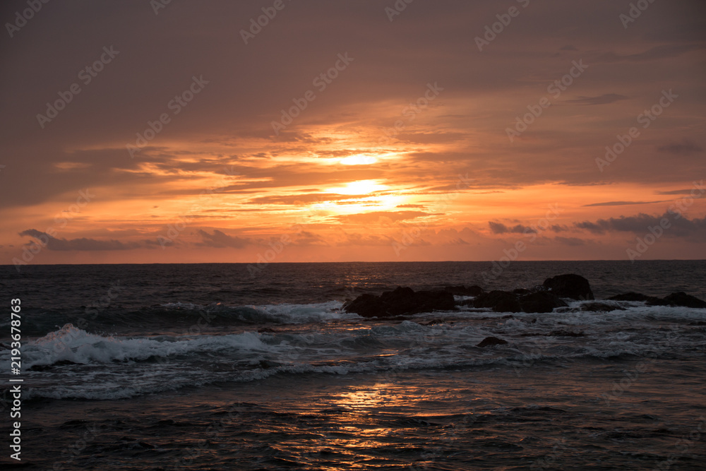 Obraz premium Dramatic red sunset sky over ocean waves in Tamarindo Costa Rica