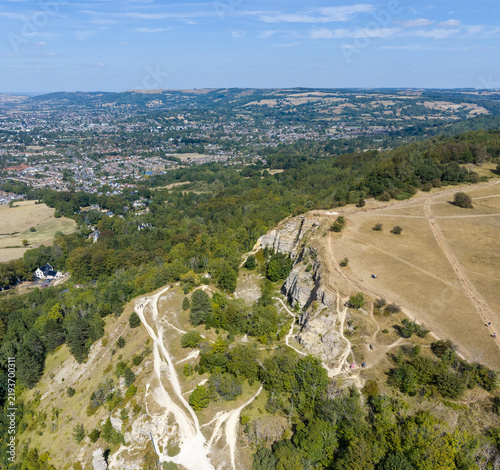 Aerial view of the limestone escarpment at Cleeve Hill with winding footpaths and lush trees overlooking the town of Cheltenham, England, United Kingdom.