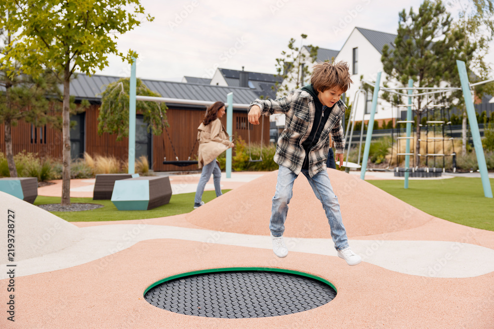 Fototapeta premium Boy jumping on trampoline in modern playground