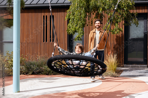 Принти на полотні Father pushing happy son on swing enjoying playtime