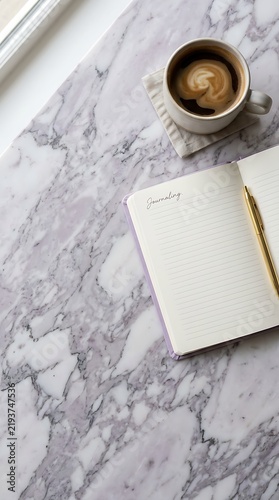 Flat lay morning journaling scene with open notebook, gold pen and latte coffee cup on white marble table background, cozy productivity and mindfulness concept.
