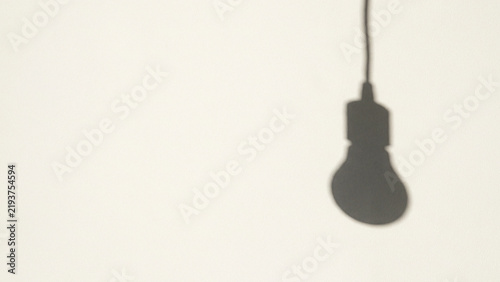 Silhouette shadow of a hanging lightbulb on a white wall background