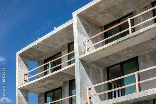 Multi level raw concrete apartment building structure under construction with temporary wooden guardrails