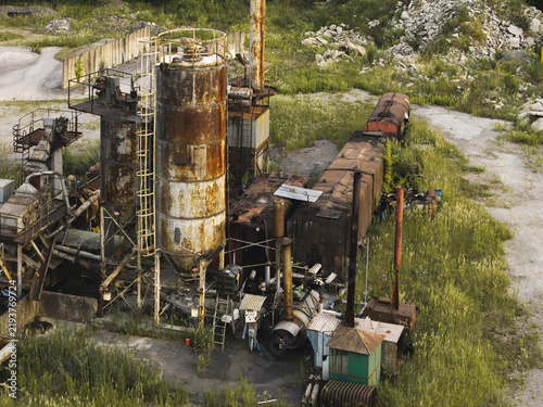Aerial view of abandoned industrial processing plant with rusted tanks, pipelines and deteriorating machinery