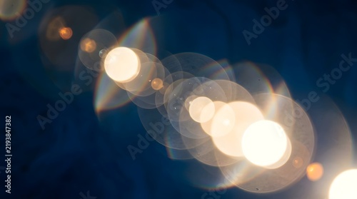 Abstract golden lens flare circles on dark blue background with light bokeh glowing circles light effect optical flare shimmering ligh