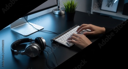Typing On A Computer Keyboard With Headphones And Monitor