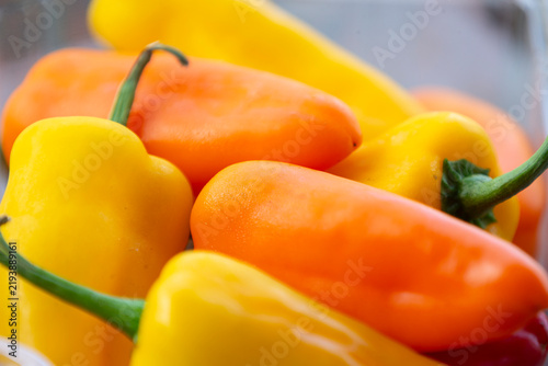 Close up of vibrant fresh orange and yellow mini sweet bell peppers.A high-quality close-up macro photograph showcasing a bright colorful heap of fresh, organic mini sweet bell peppers (capsicum). 