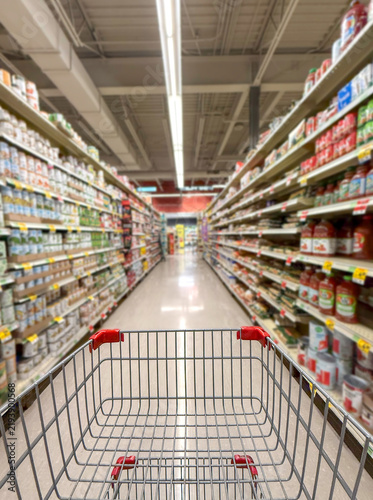 Close up of shopping cart in supermarket aisle.	