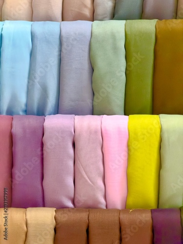Colorful hijab fabrics neatly arranged on display, showcasing variety of pastel and vibrant colors for fashion and textile background use