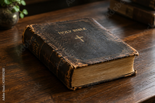A closed, century-old family bible with worn leather on a wood table.