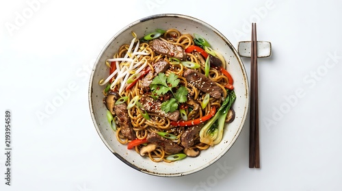 Asian noodle stir fry dish served in white bowl with chopsticks on white tabletop