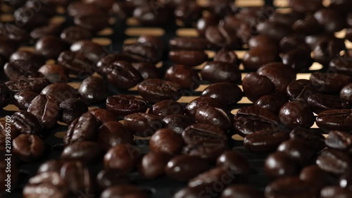 Close-up of roasted coffee beans being heated over flames during the coffee roasting process, highlighting the beans and warm roasting environment.