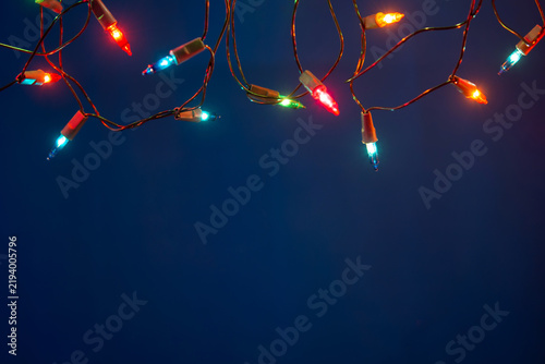 Christmas lights string on blue background with copy space