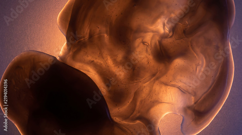 Glowing translucent material revealing intricate fluid texture with back light on a dark background in a close-up abstract view.