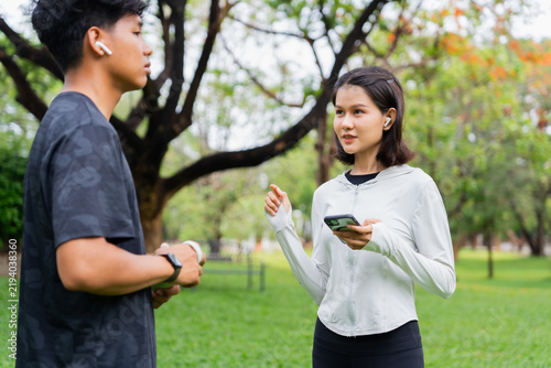 Asian sporty man and woman talking together in public park