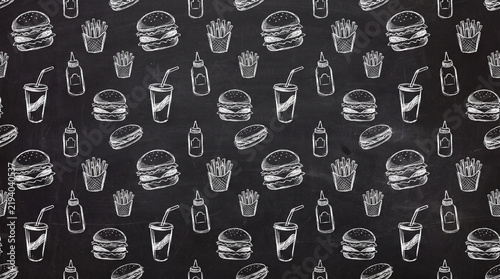Fast food chalk sketches with burger, fries, soda, and sauce bottle on blackboard background
