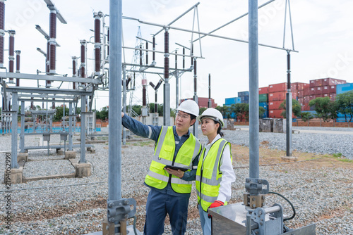 Foto Substation patrol inspection by two engineers at a disconnect switch, one pointing ahead while holding a tablet in the switchyard