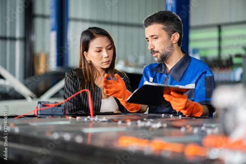 Obraz na plátne Customer hears the garage service technician explain a test result from his clipboard, the insulation tester on the pack in front