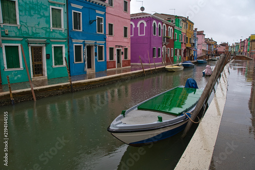 Принти на полотні Canal with a boat in front of colorful houses on a rainy day in Burano, Venice