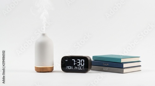 Aromatherapy diffuser with alarm clock books and wellness accessories arranged on clean background representing relaxation sleep self care and peaceful home lifestyle