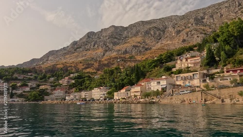 Croatian coastal village beneath rugged mountain cliffs beside calm sea