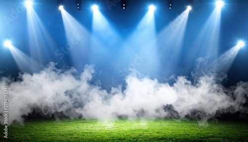 Dramatic stadium stage with bright spotlights and fog on green grass