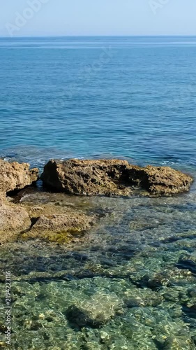 Vertical video of the rocky shore of Crete Island with blue clear Mediterranean sea water. Greece