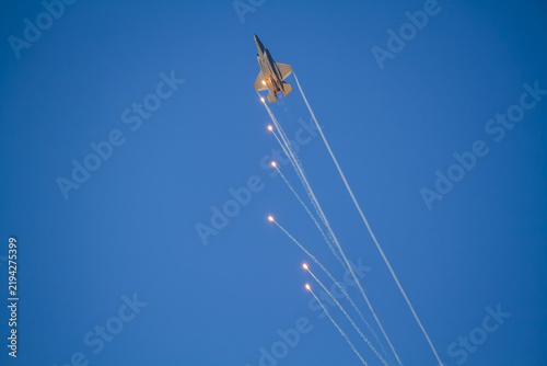 F-35A Lightning II fighter aircraft flying across a blue sky with visible vapor trails and clouds below, photographed in side profile showing its distinctive stealth aircraft design.