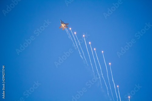 F-35A Lightning II fighter aircraft flying across a blue sky with visible vapor trails and clouds below, photographed in side profile showing its distinctive stealth aircraft design.