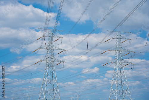 Fotografie Two electricity pylons with power lines against blue sky