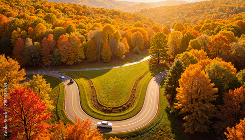 Classic car driving on winding road through autumn trees, seasonal beauty