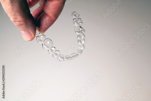 Hand holding clear aligner for teeth straightening treatment with copy space