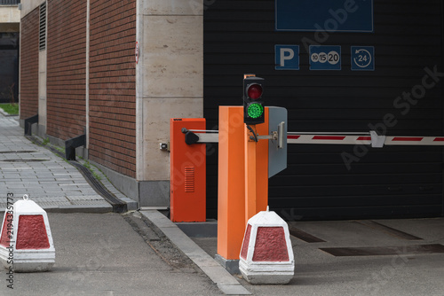  Parking garage entrance with automatic barrier and green traffic signal. Parking issues in modern cities.