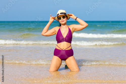 Woman in purple bikini happy on beach