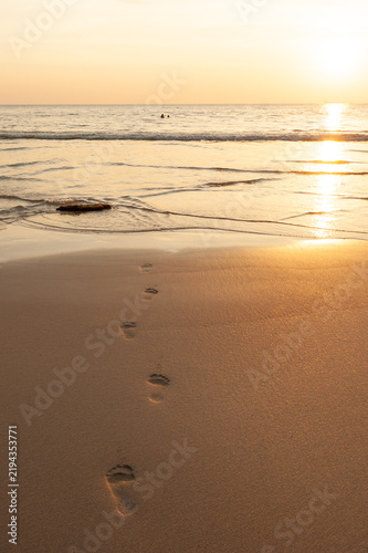 A pair of footprints on the sunset beach.