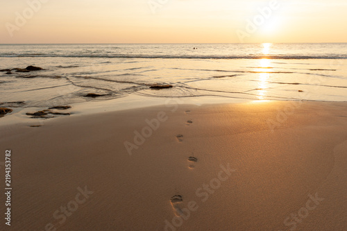 A pair of footprints on the sunset beach.