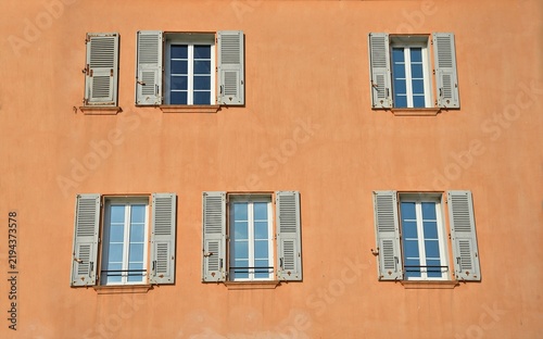 Provençal style house facade with a Venetian stucco wall and grey wooden window shutters in Saint-Tropez, French Riviera France.