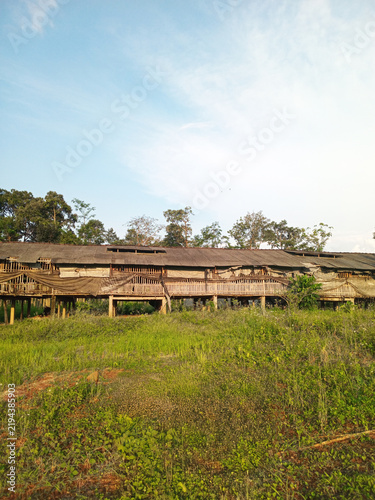 Traditional wooden poultry farm building standing on a grassy field under bright sky