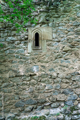 A weathered wall of a medieval building made of stones of different shapes and sizes, bonded with lime, with a narrow stone window. Amlivi, Amlevi complex. Kvemo Kartli, Tetritskaro, Georgia