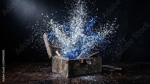 Wooden box unboxing with exploding party favors and shiny confetti. Festive celebration supplies bursting from a container on dark background.
