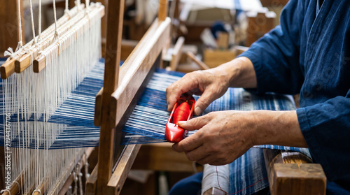 Obraz na płótnie Weaver's Hands Guide Red Shuttle Through Blue Warp Threads on Loom