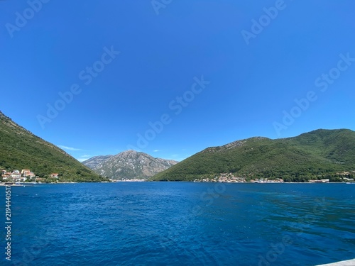 Scenic panoramic view of the Adriatic sea with calm blue water and coastal mountains under a midday sky in Tivat bay.