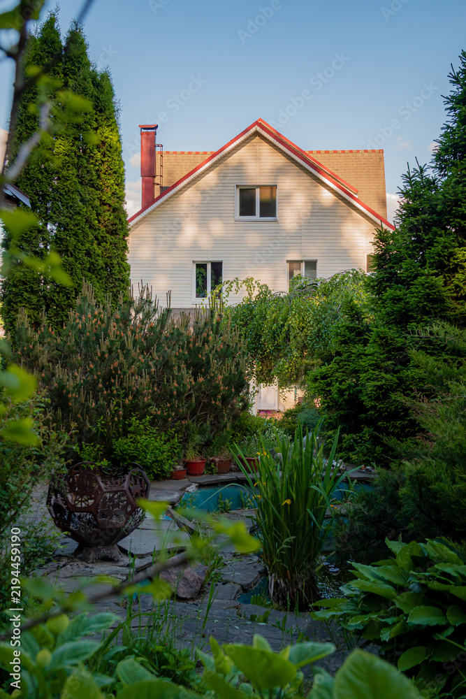 Obraz premium Charming garden view showcasing a cozy house surrounded by lush greenery