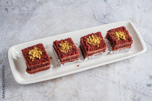 Delicious red velvet cake squares topped with crunchy nuts on a sleek platter