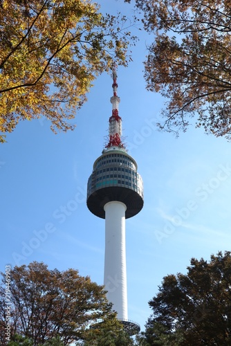 N Seoul Tower framed by autumn trees with blue sky, Korean landmark scenery showing colorful fall foliage and clear weather background