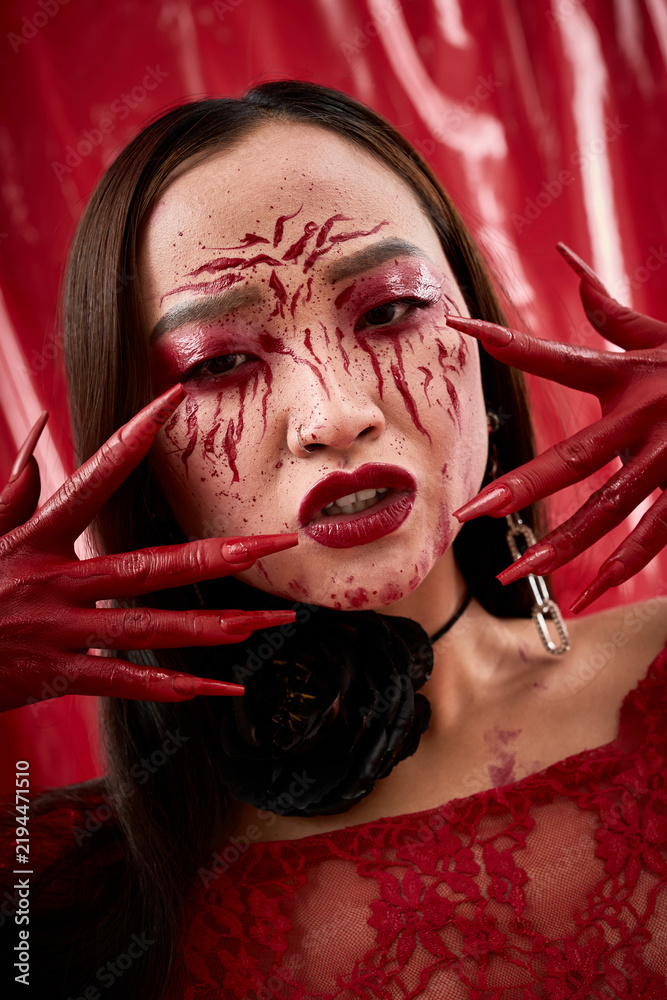Naklejka premium Young Asian woman embodies dark royalty with bloody vampire allure for Halloween