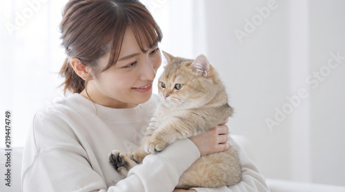 Fototapeta 部屋で愛猫を優しく抱きしめる若い女性