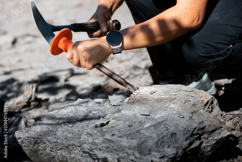 Foto Medium close-up shot of a geologist using a hand chisel with a protective handguard and a rock hammer pick to carefully extract stone and mineral samples during field work