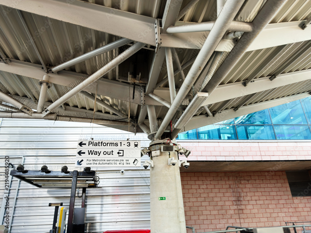 Obraz premium Platform signage and canopy structure at a modern urban train station showing way out directions and structural steel pillar with security cameras